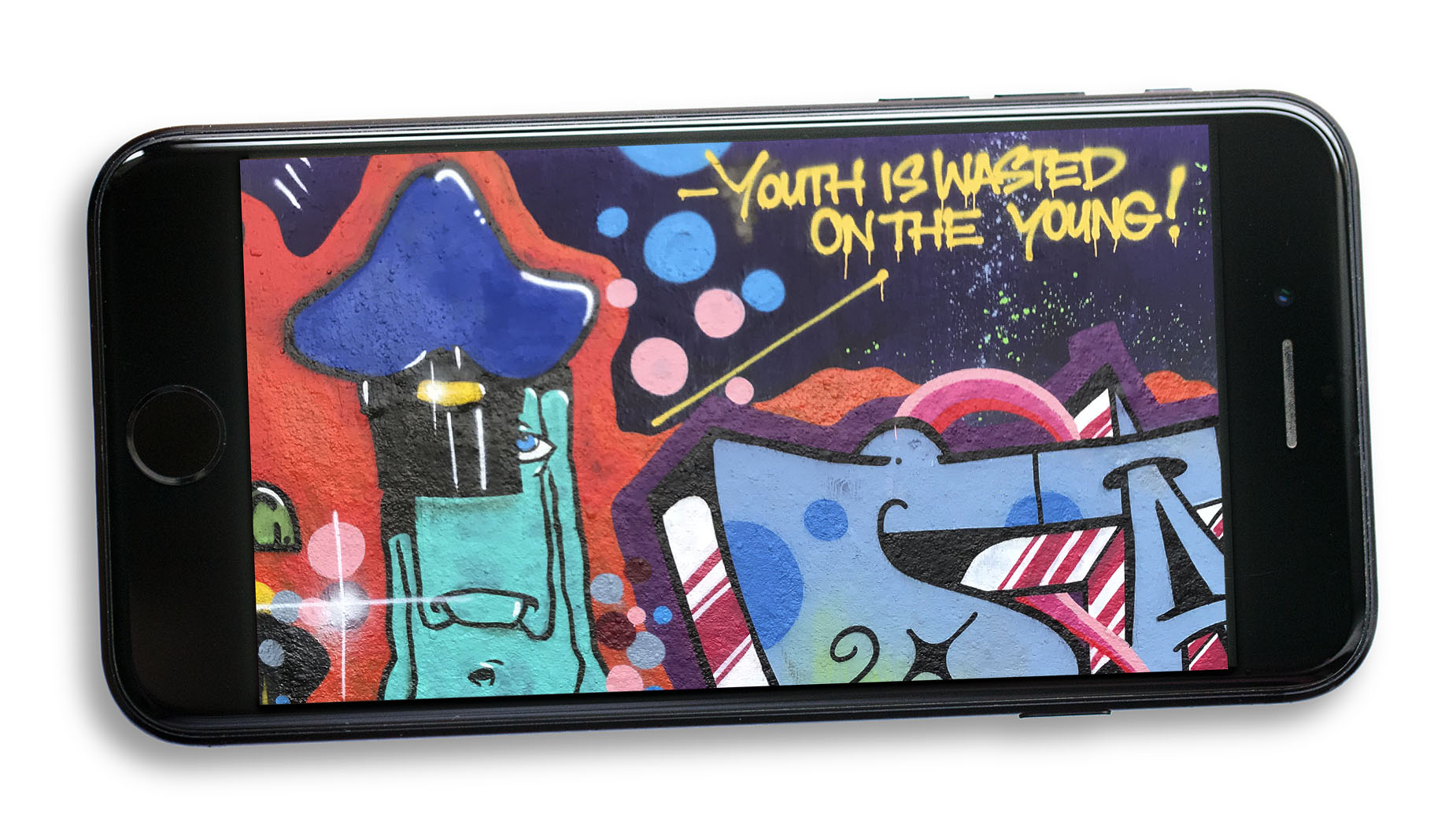 Bild på graffitimålning på en mobiltelefon. På bilden står det "youth is waisted on the young".
