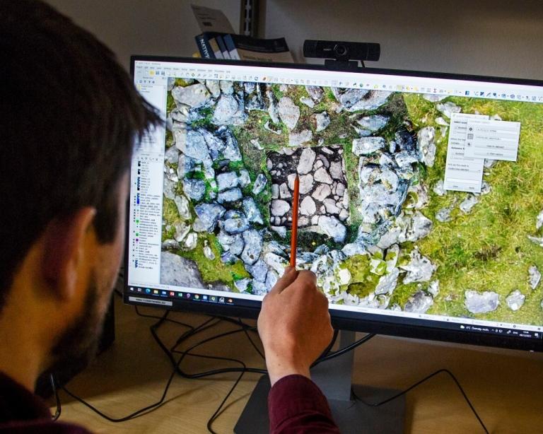 Man pekar med en penna på en datorskärm som visar en karta.