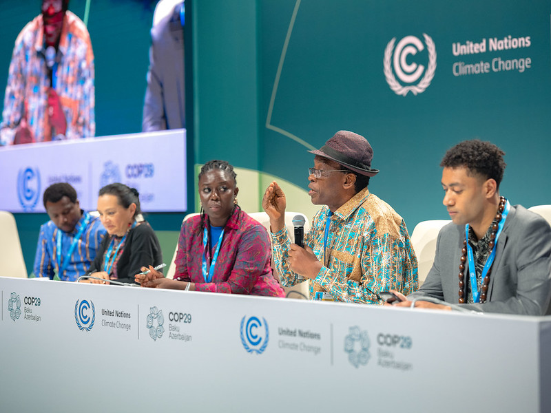 Fem delegater på ett podium vid COP29, en talar