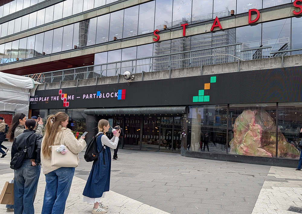 Studenter tittar på spelet Partiblock som visas på Kulturhusets fasad.