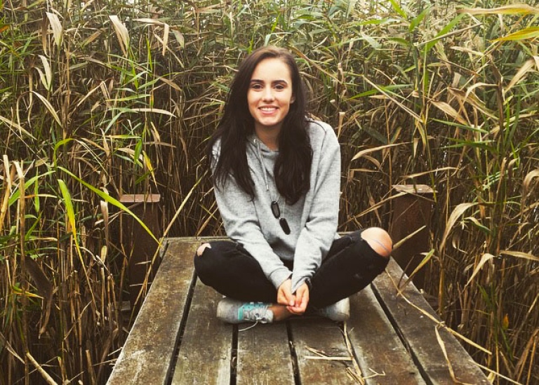 Deborah Suter, exchange student, sitting on a pier surrounded by reeds. 