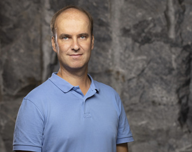 A man (Christophe Premat) standing in front of a rock wall.