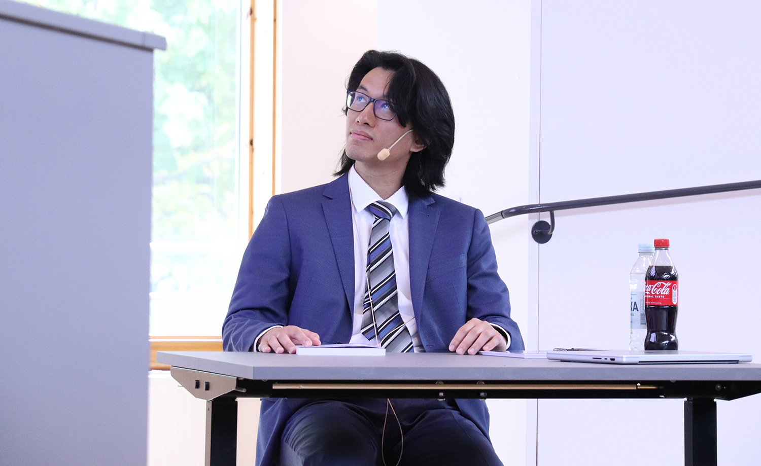 Chek Yin Choi sitting at a desk at his defense.