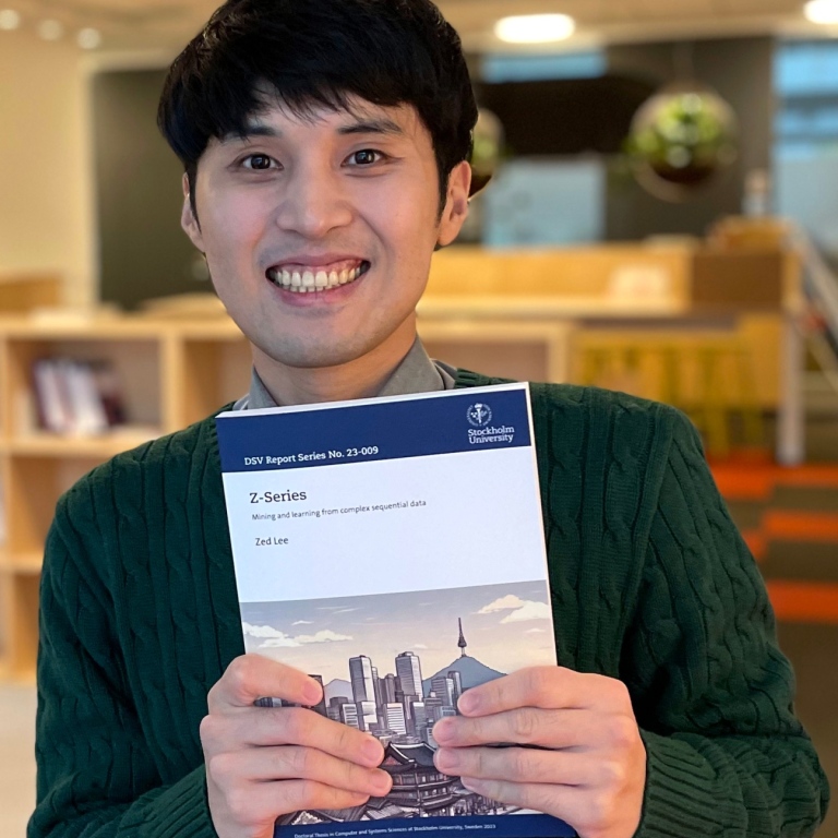 Zed Lee holding his PhD thesis in his hands.