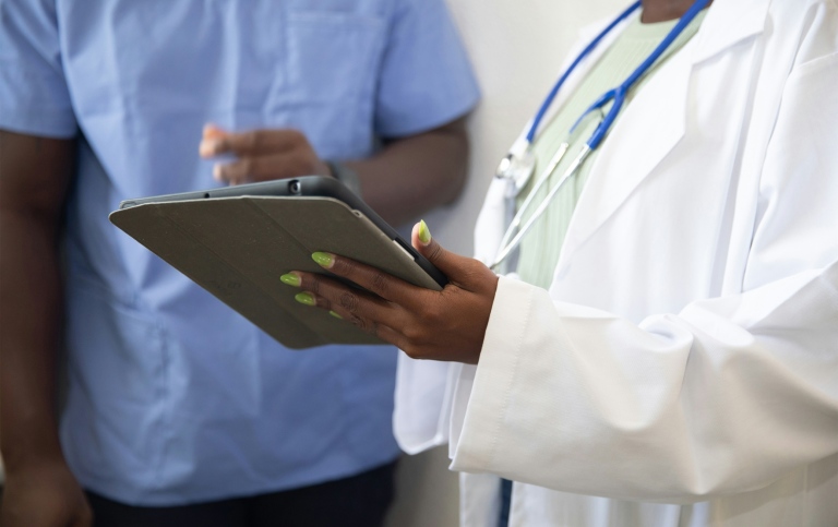 Two health care professionals discussing holding a tablet.