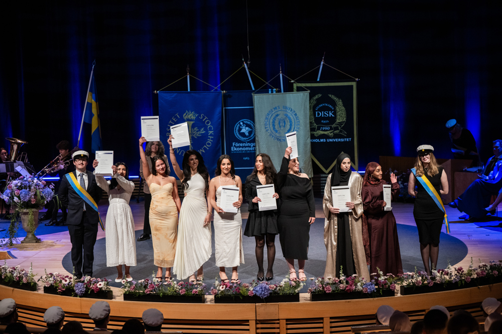 Två kvinnliga studenter och två manliga studenter på Västerbron med Stadshuset i bakgrunden.