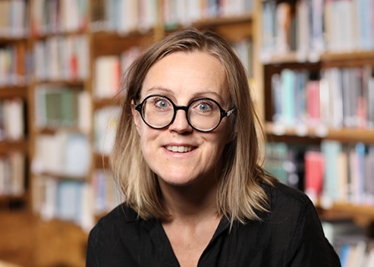 Victoria Fareld framför en väg med bokhyllor.