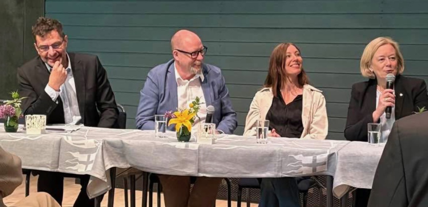 Fyra personer sitter framför publik och håller panelsamtal.