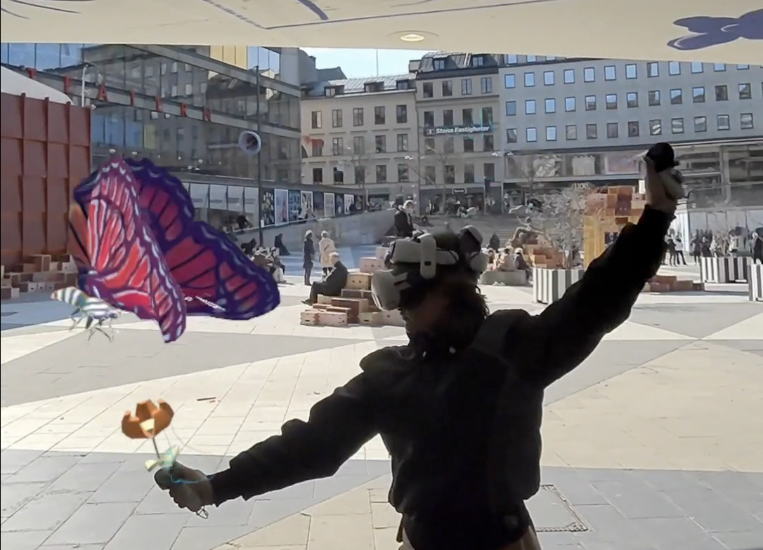 Dansare i MR-headset med en virtuell blomma och fjäril på Sergels torg.