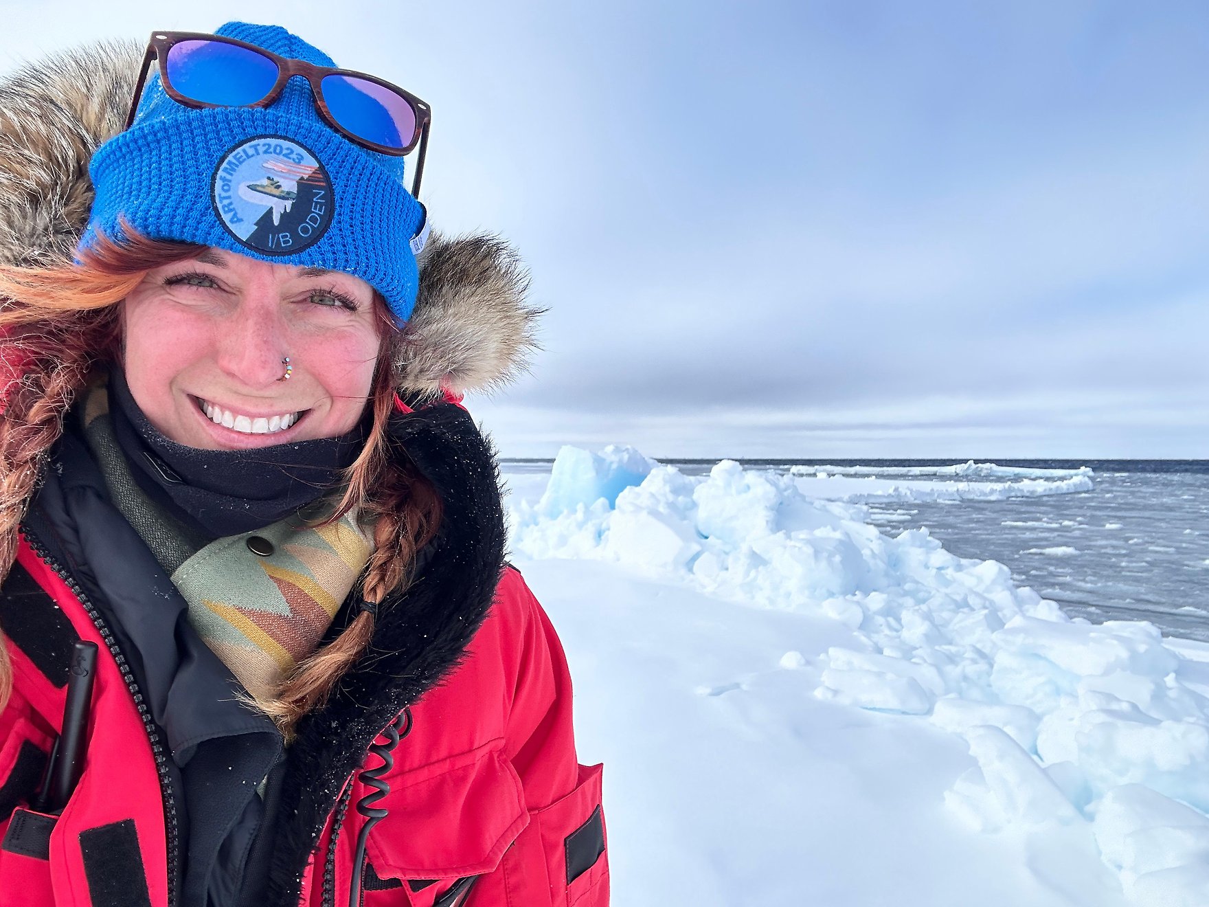 researcher smiling and looking into the camera, with ice and snow on the background