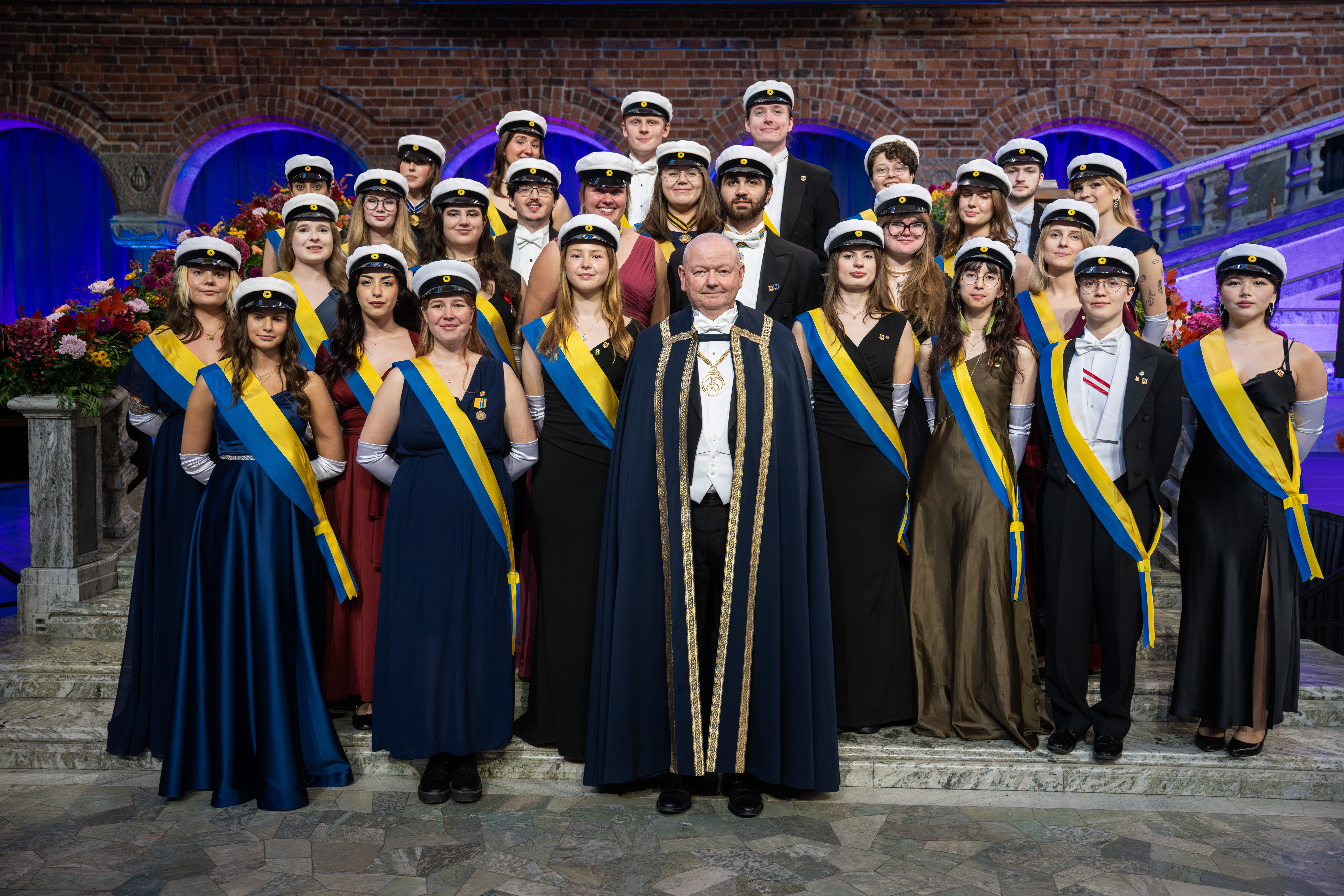 Rektor Hans Adolfsson iförd rektorskåpa och rektorskedja tillsammans med studentmarskalkar vid promotionshögtid i Blå hallen i Stockholms stadshus. Foto: Johanna Säll