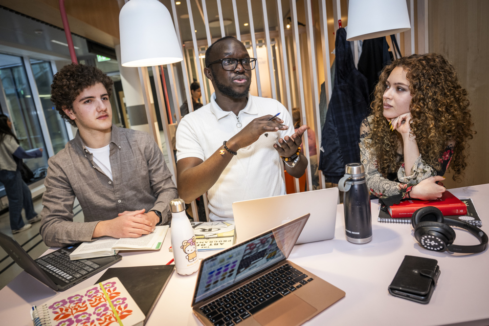 Studenter sitter vid ett bord och diskuterar med varandra.