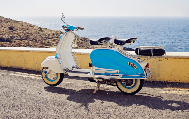Vintage blue and white scooter parked near the coast