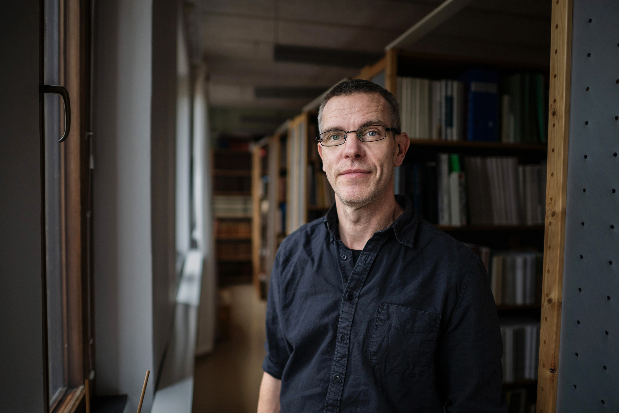 Porträtt av marinarkeologen Niklas Eriksson framför en bokhylla.