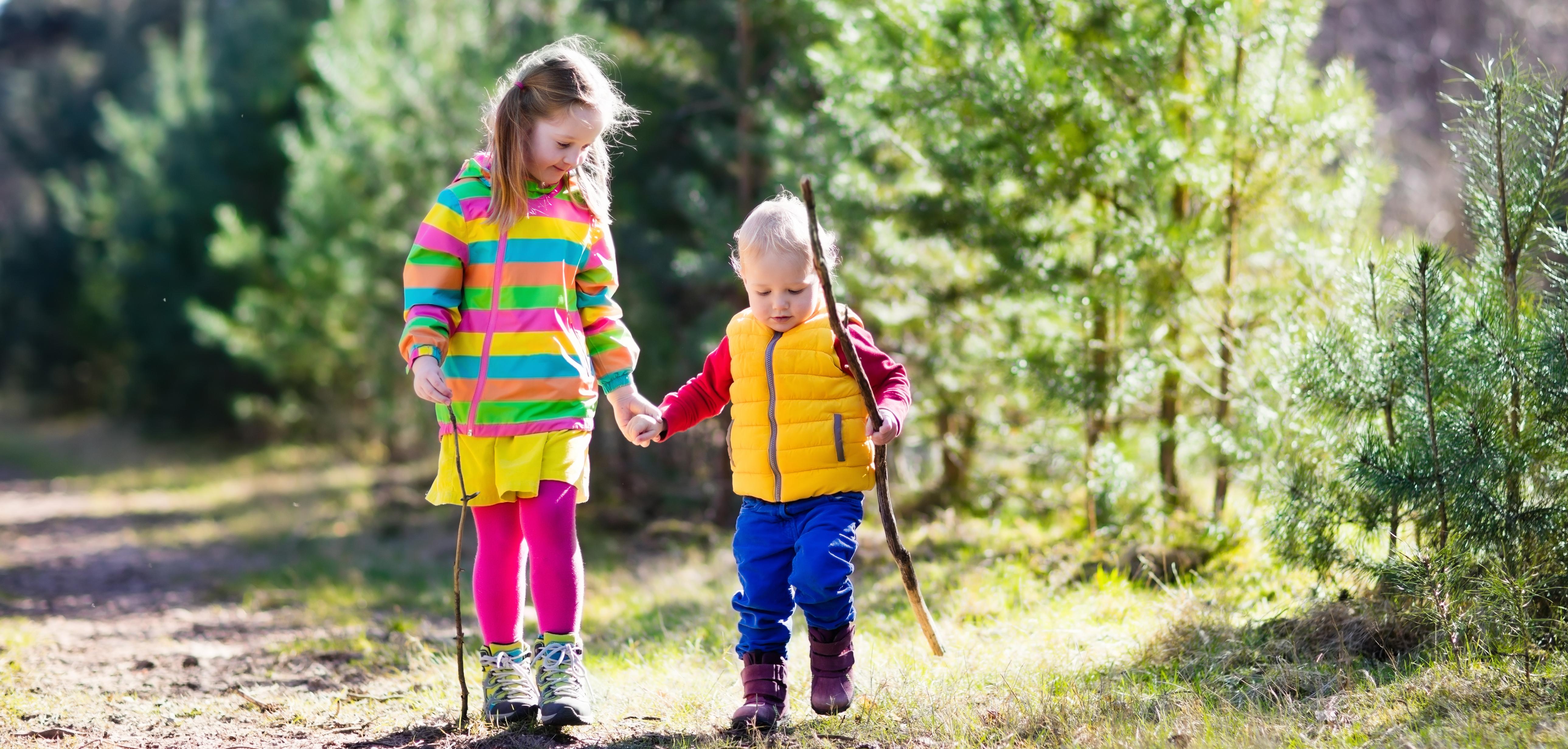 Boy and girl walking in forest holding each other hands