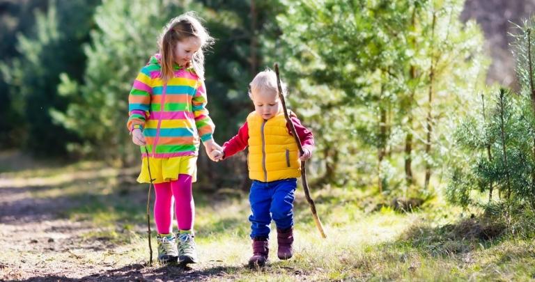 Pojke och flicka promenerar i skogen och håller varandra i handen