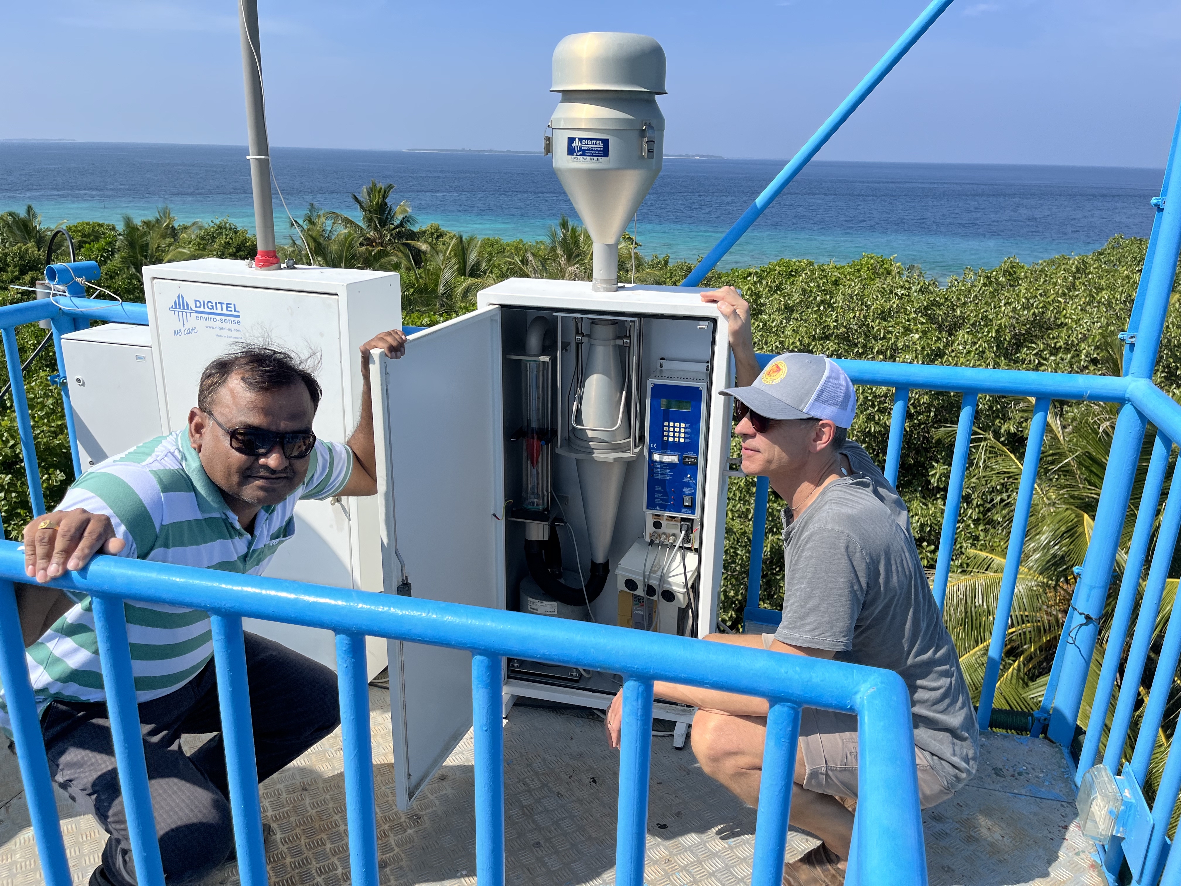 Two men at a scientific instrument by the sea