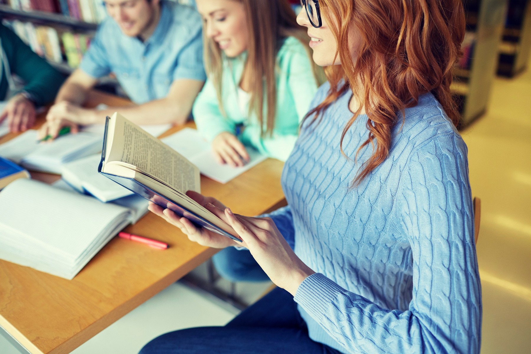 Studenter som sitter vid ett bord och läser böcker