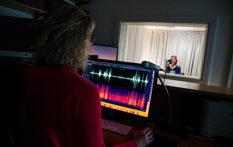 Inspelningsstudio Talaren sitter i inspelningsrummet och ljudteknikern leder inspelningen