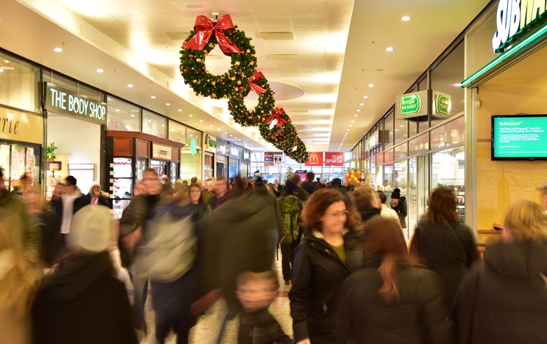 Många människor som trängs i en julpyntad shoppinggalleria