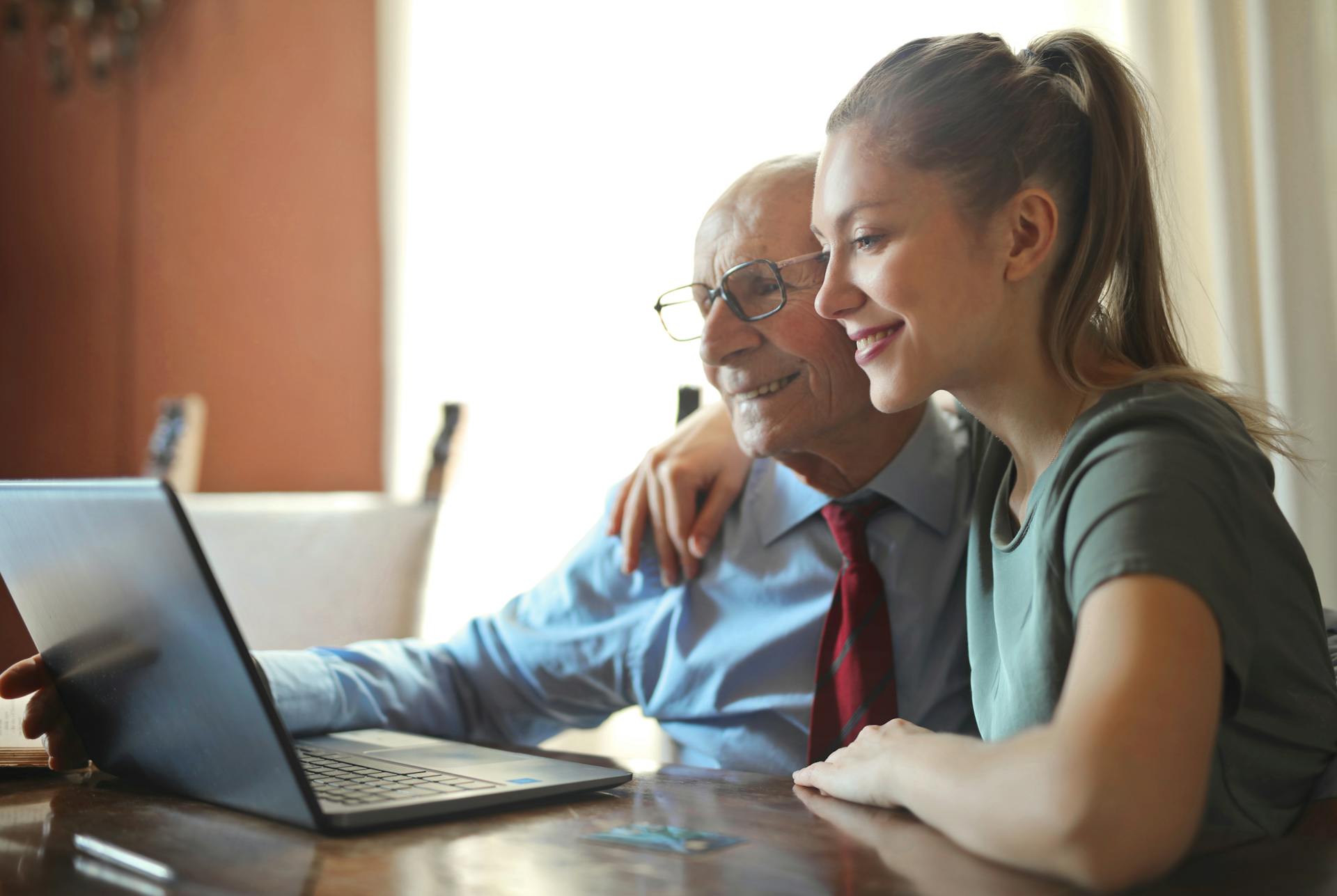 Older person and younger person intimately looking at computer.