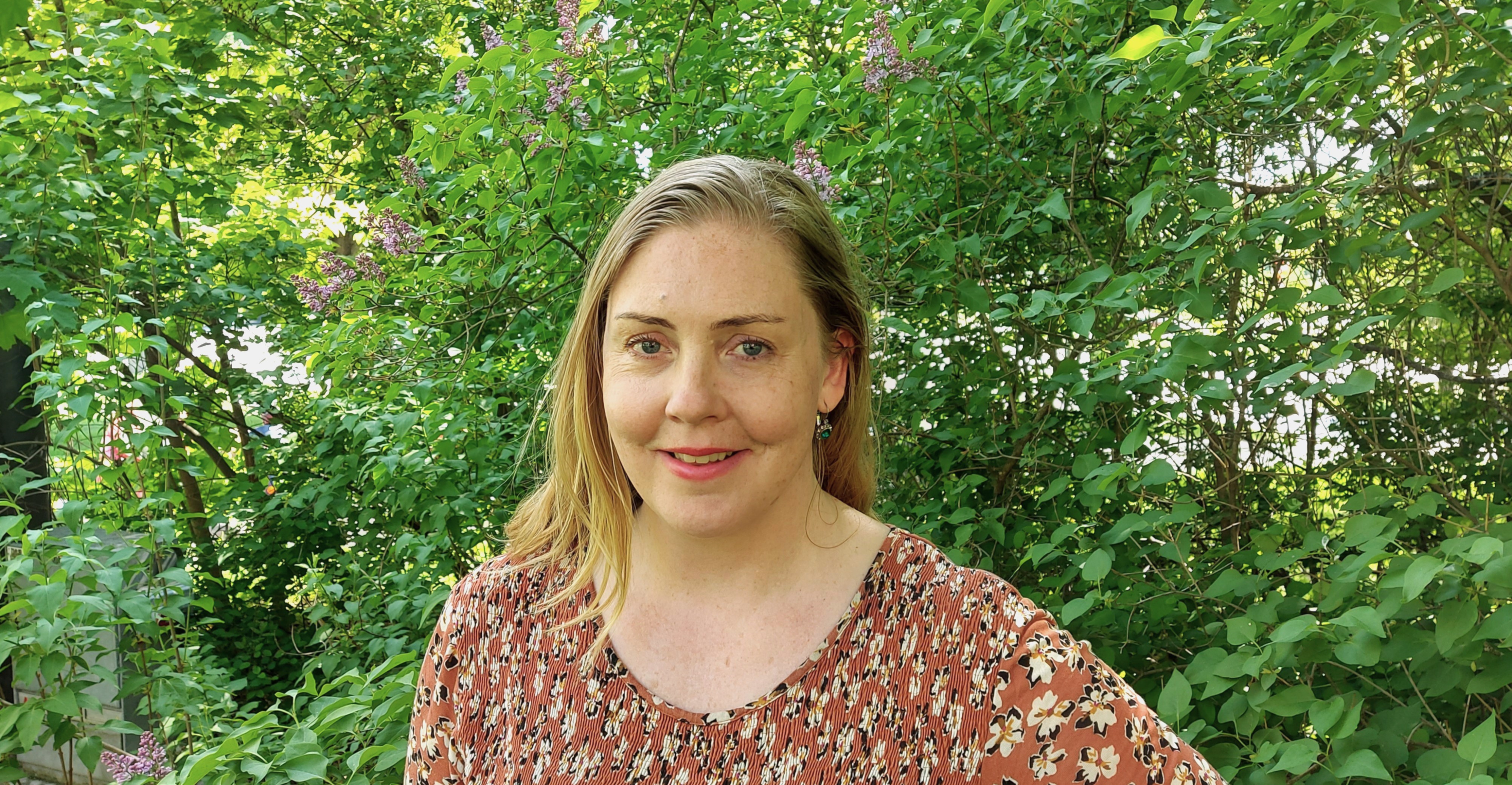 Caroline framför syrenhäck.