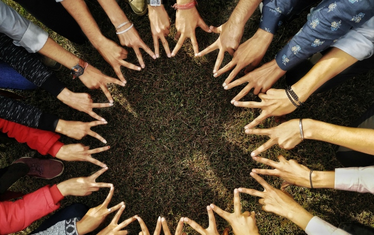 A group of people building a star with the peace-sign. Photo: Abhay Yadav from Pexels