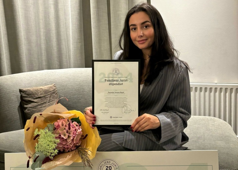 Parmida Tavana Nejad sitter i en soffa med stipendiebeviset i händerna