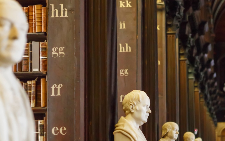 Statyer av filosofer på rad i bibliotek.