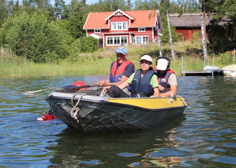 Tre forskare i en liten motorbåt undersöker en vik.