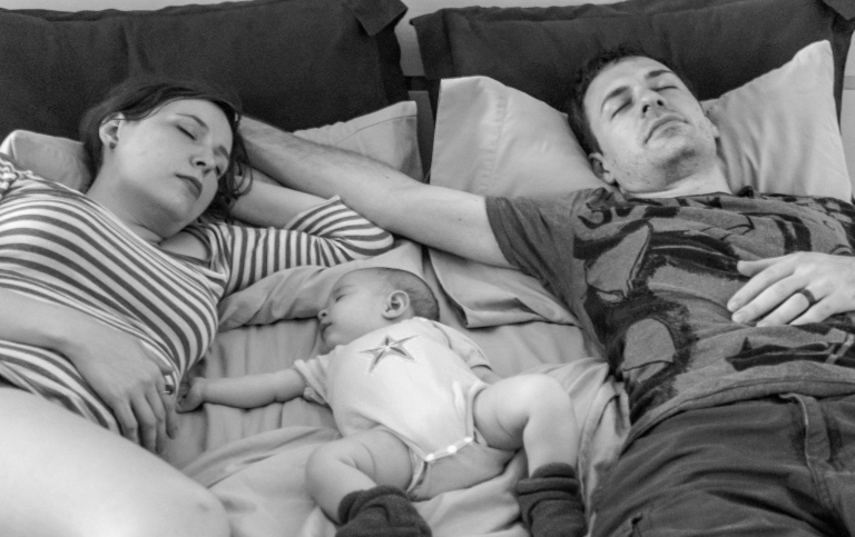 Föräldrar och bebis ligger och sover.