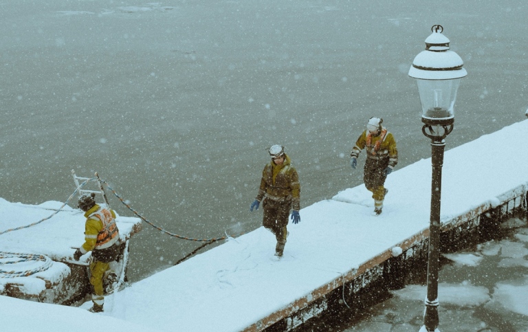 Uniformed personell working at the docks in a snow-storm