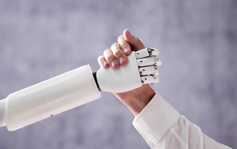 En robothand och en mänsklig hand förenas i ett handslag.