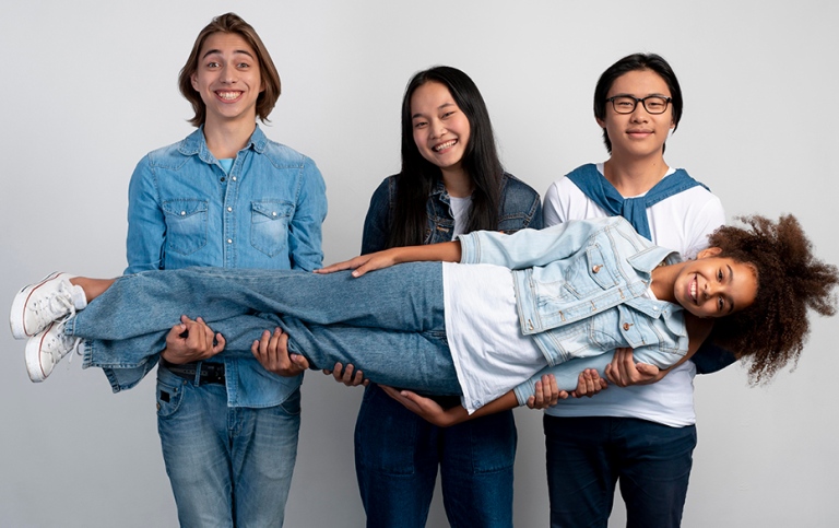 Three teenagers lifting up a friend