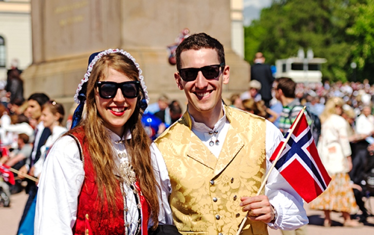 En kille och en tjej klädda i norska folkdräkter.