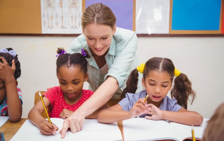 Teacher giving instructions to two young learners.