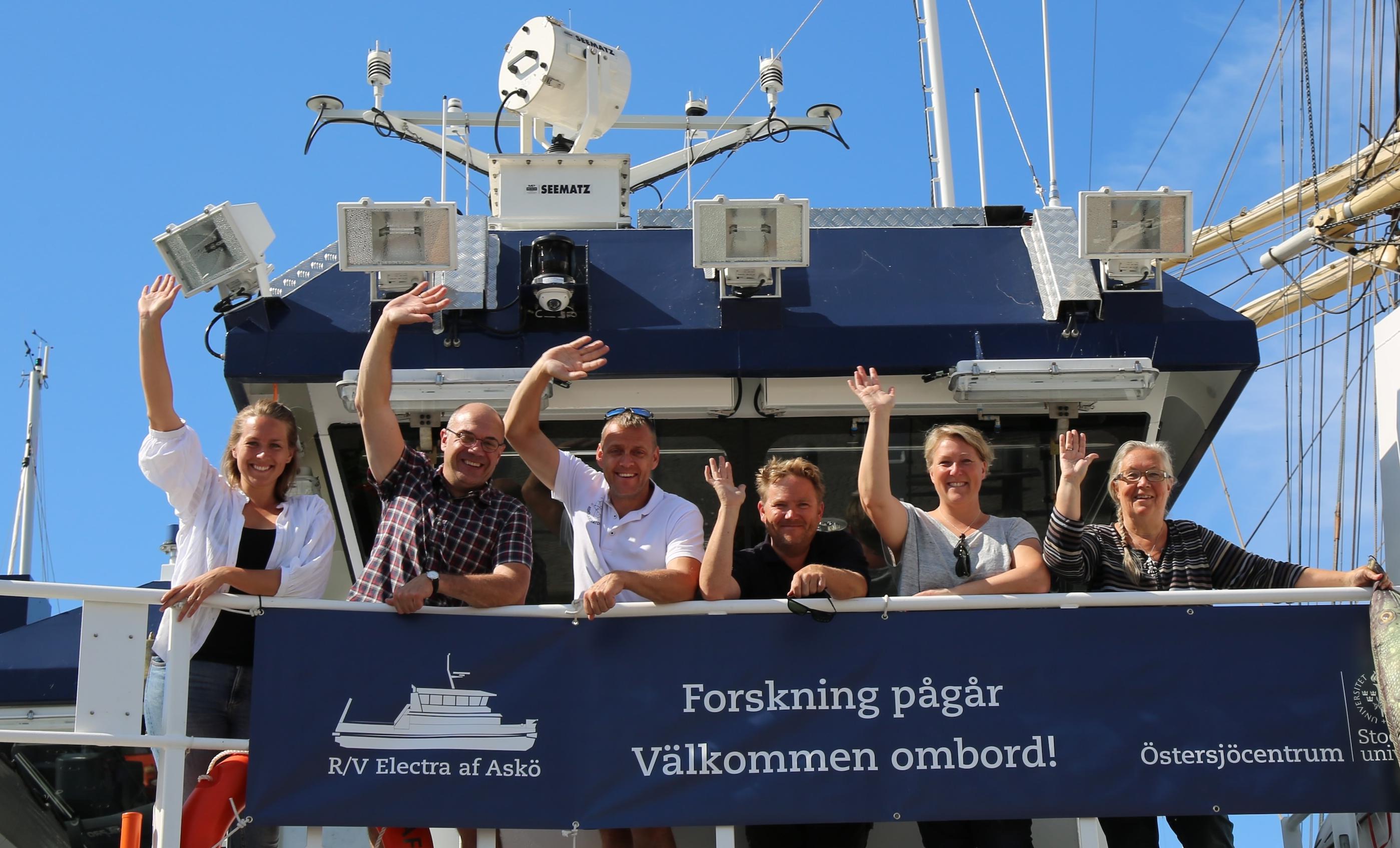Flera medarbetare från Östersjöcentrum står på fartyget Electra och vinkar till kameran.