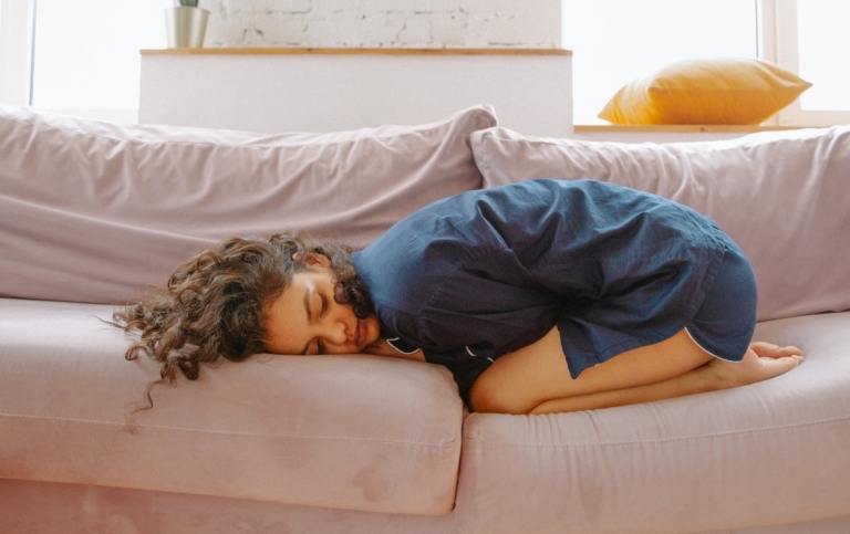 Woman with stomach pain in sofa.
