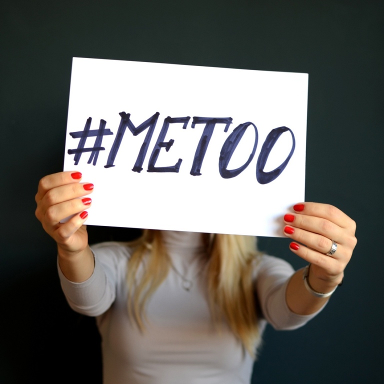 Kvinna som håller upp #metoo-skylt framför ansiktet.