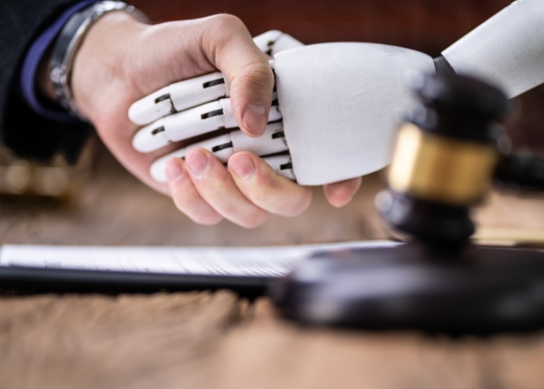 Närbild på en mänsklig hand som skakar hand med en robot. I förgrunden syns en domarklubba