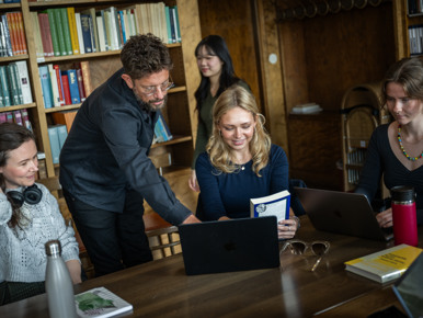 Lärare instruerar student vid dator.