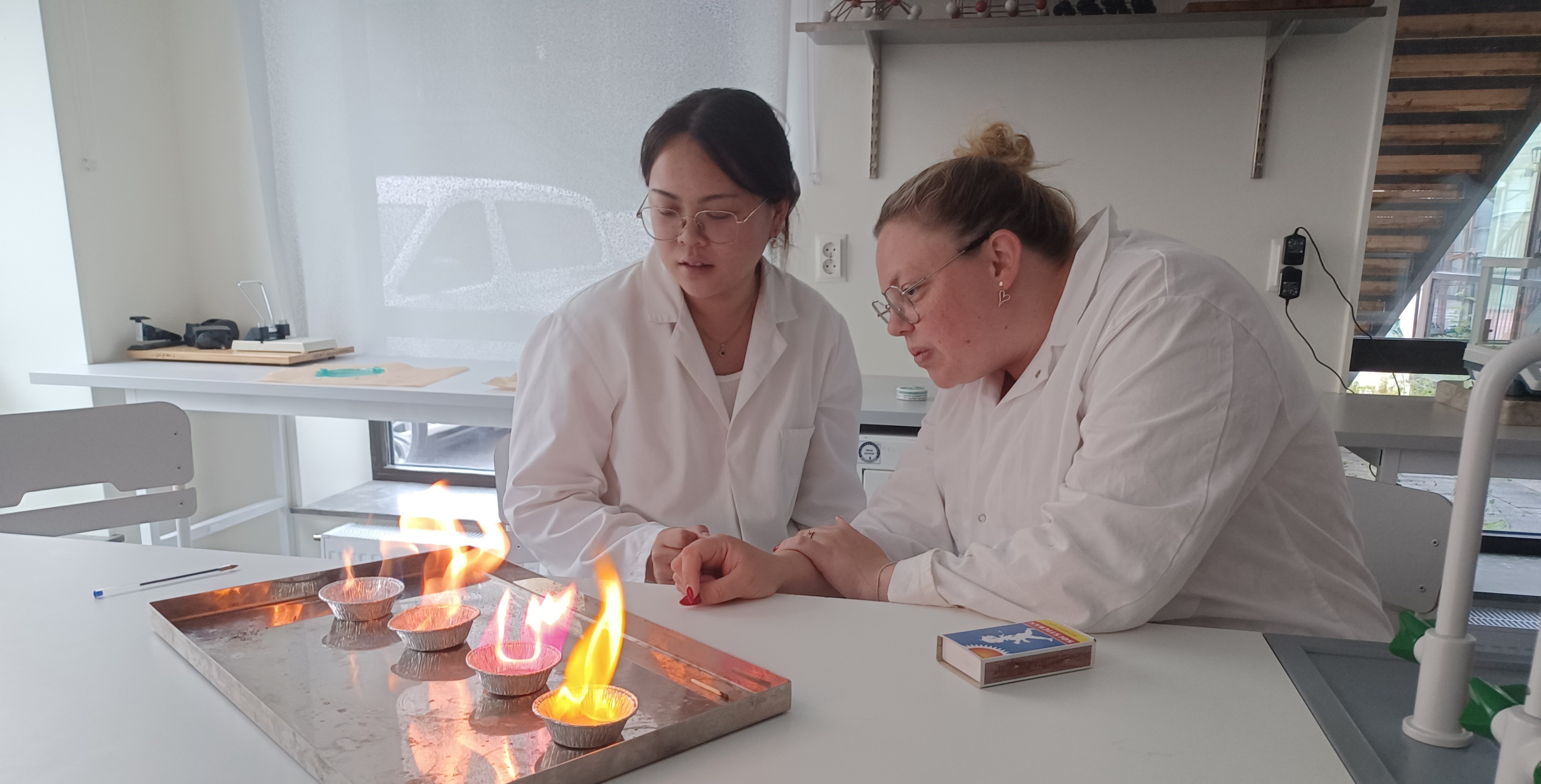 Två lärare som genomför laborationen lågfärger.