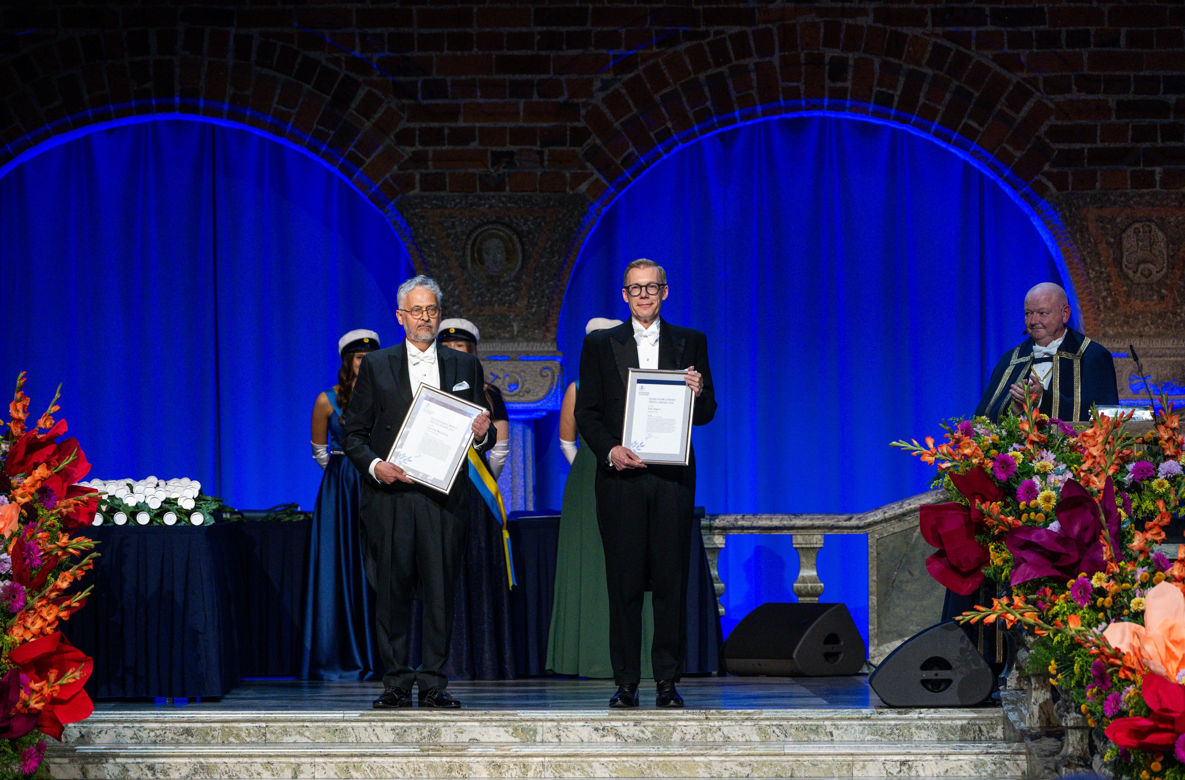 Two men in dress suit holding diplomas