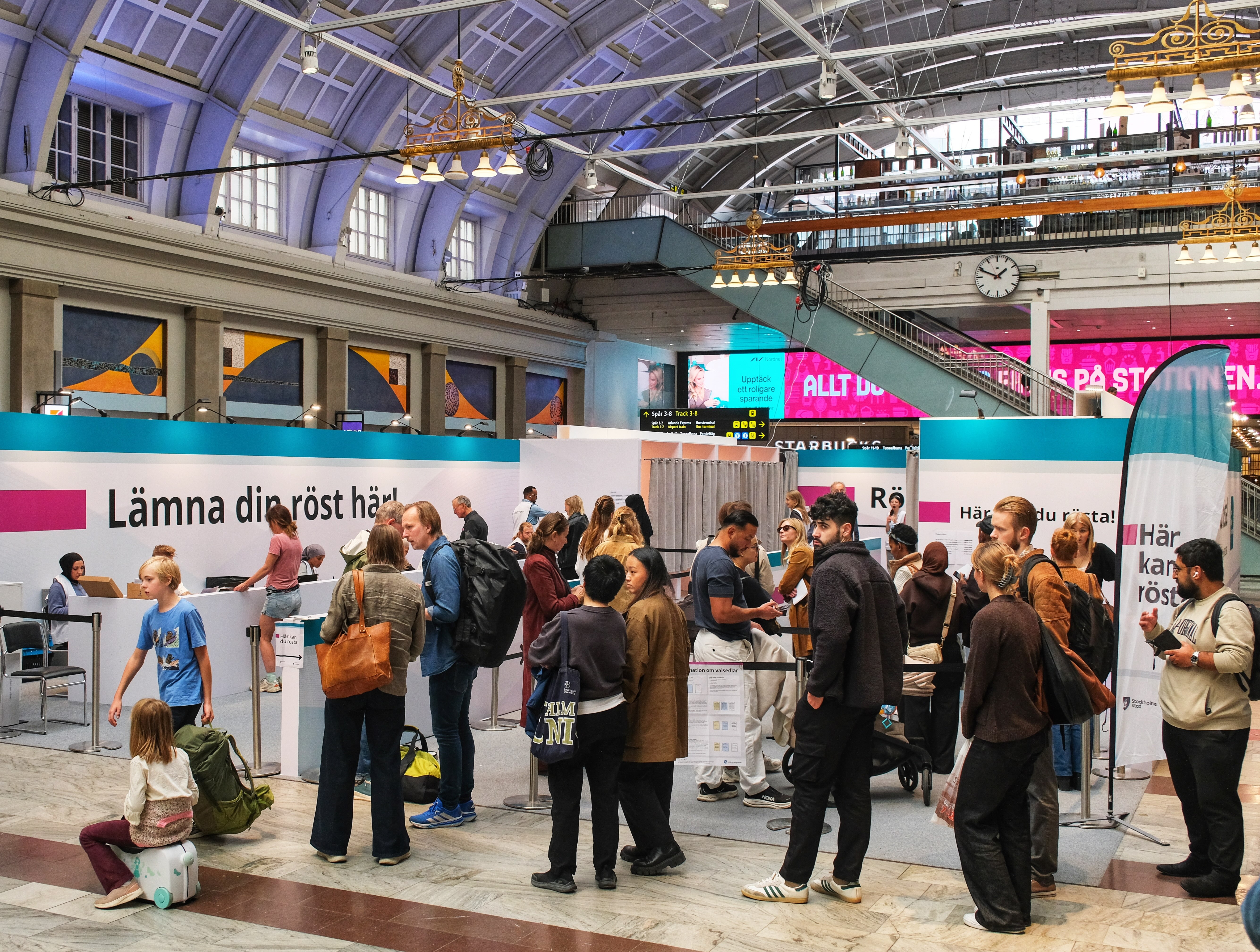 STOCKHOLM, SVERIGE - 13 SEPTEMBER 2026: Människor köar och lämnar sina röster i en tillfällig röstningslokal inuti Stockholms centralstation under den svenska valdagen. Foto: Krister Hägglöf/Mostphotos