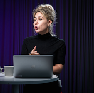 Photo of Sabina Čehajić-Clancy talking at a podium/stand table.