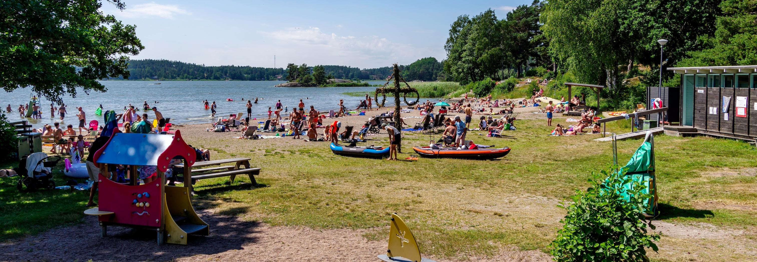 Trosa havscampings badplats är fylld av badande människor.