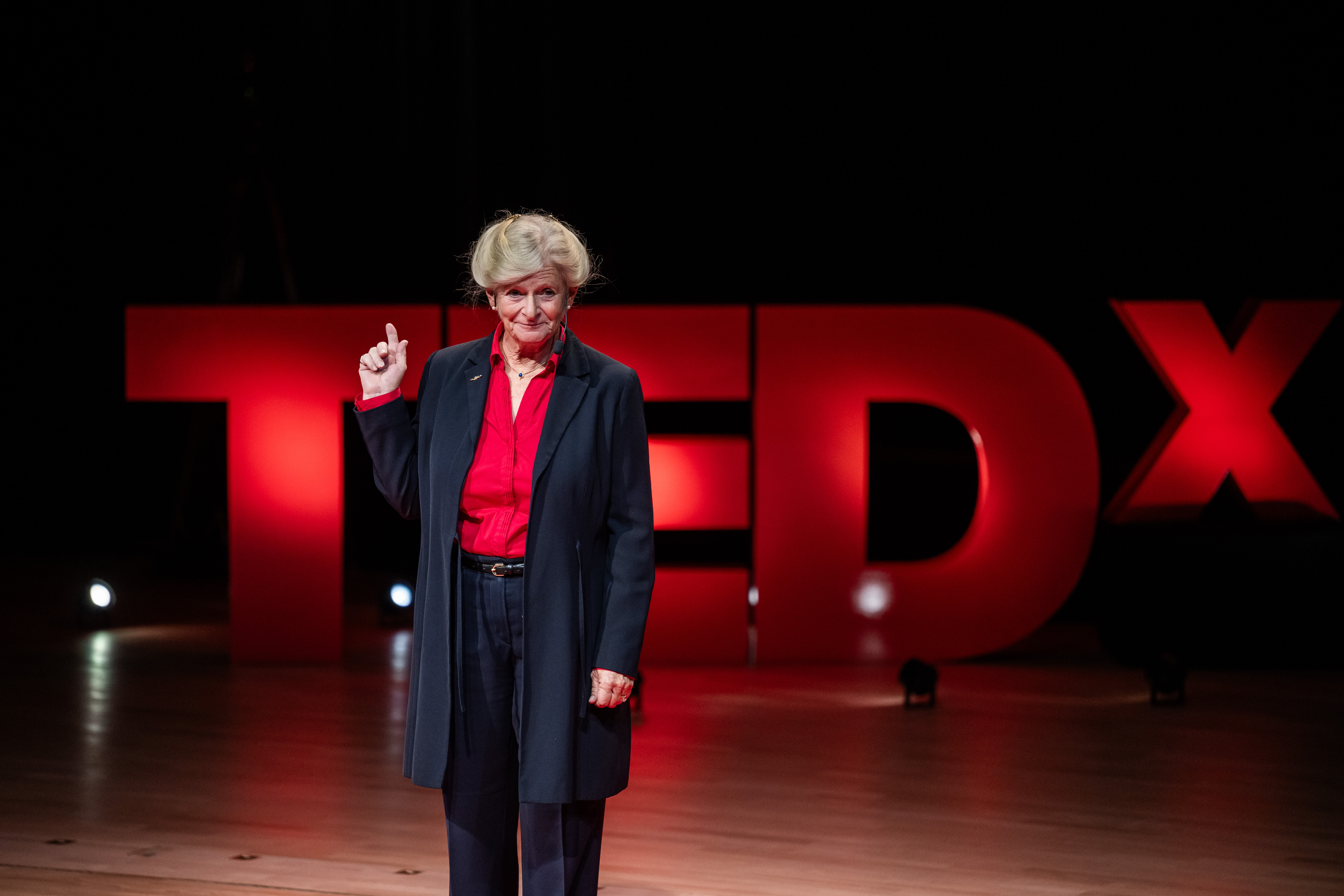 Kvinna håller upp fingret i luften. I bakgrunden står det TEDx.