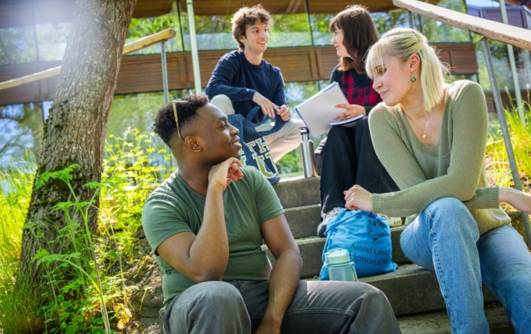Studenter sitter i trappa utomhus och pratar.