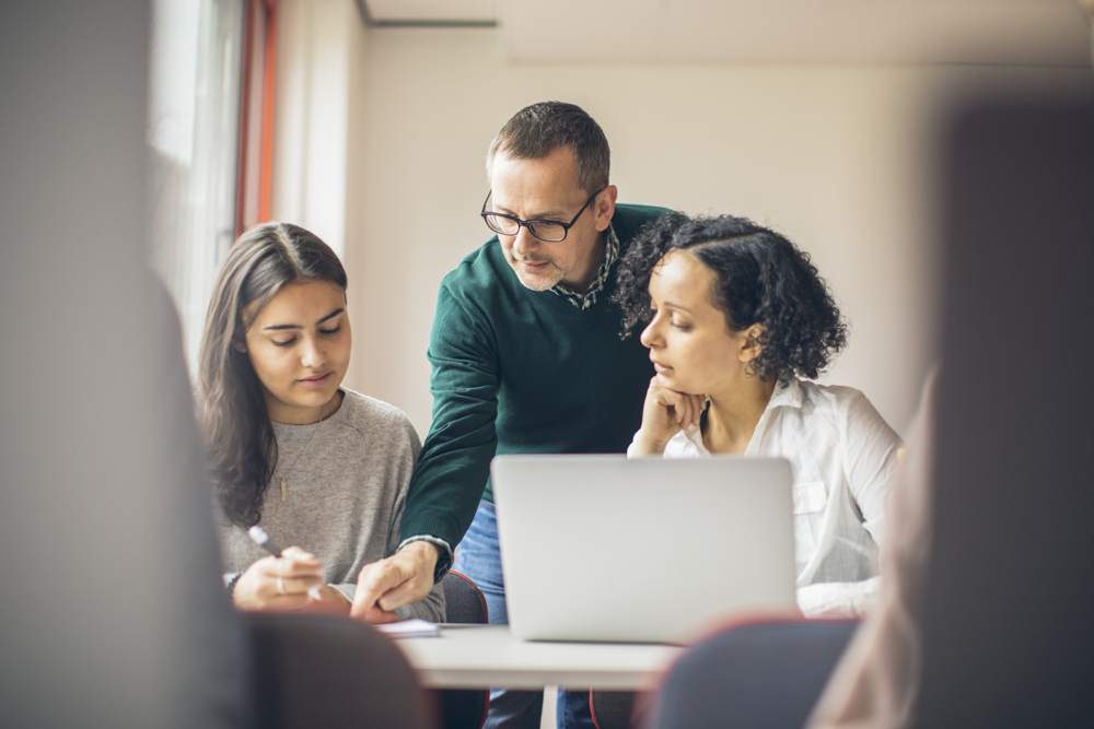 A teacher and two students in front of a computer