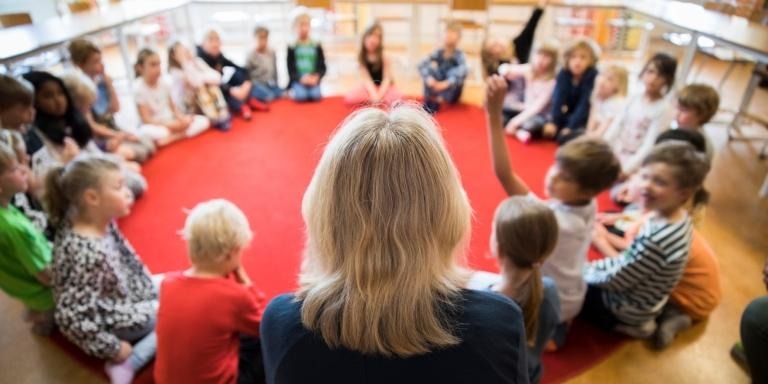 Förskoleklass sitter i ring med lärare